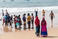 Two women in colorful clothes walking on a crowded beach in North Goa