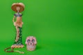 Calavera de la Catrina statuette next to a wooden rosary and a pink skull Royalty Free Stock Photo