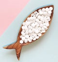 Calcium pills in a wooden dish in the form of a fish.