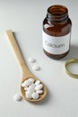 Calcium supplement pills, spoon and bottle on white table Royalty Free Stock Photo