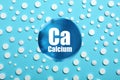 Calcium supplement pills on turquoise background, flat lay