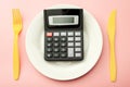 Calculate expensive food spending costs, counting calories and weight loss program concept with calculator onn empty plate, yellow