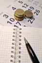 Calculating Expenses concept. Pen, calendar, notebook, and coins. Royalty Free Stock Photo