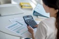 Brunette female sitting at her desk, holding calculator