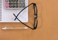 calculator, ballpoint pen, empty notebook, eyeglasses on office