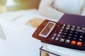 Calculator and binders with papers are waiting to be processed by business woman or bookkeeper working at the desk in Royalty Free Stock Photo