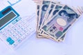 Calculator with blurred Japanese currency yen bank notes and coin on finance chart and graph background, finance planning concept Royalty Free Stock Photo