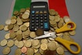 A calculator with coins and a scissors over an Italian flag. Tax cut concept