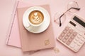 Calculator, a cup of coffee with a beautiful pattern and a notepad on a pink background. Place for text Royalty Free Stock Photo
