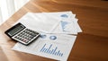 Calculator and Financial Documents on Wooden Desk with Graphs Royalty Free Stock Photo