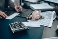 Calculator front of Investors hand writing bank check and money,  piggy bank on the table. Business saving money and financial Royalty Free Stock Photo