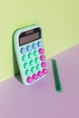 Calculator and green pen on a purple green background Royalty Free Stock Photo