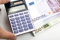Calculator in the hand and a bundle of banknotes 500 and 200 euros close up Royalty Free Stock Photo