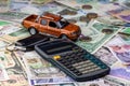 Calculator, keys and pickup toy car on a variety of national currency banknotes background.  Concept of the cost of purchasing, Royalty Free Stock Photo