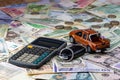 Calculator, keys and pickup toy car on a variety of national currency banknotes background.  Concept of the cost of purchasing, Royalty Free Stock Photo