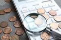 Calculator, magnifying glass and coins on stone table, closeup. Search concept