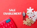 Calculator,miniture people and puzzle with text SALE ENABLEMENT