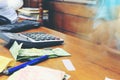 Calculator and money thai banknote with white notebook paper, pen on wooden table at home office. The concept of financial planni Royalty Free Stock Photo