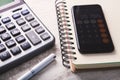 Calculator notebook and smartphone on a wooden background