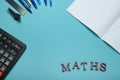 Calculator, notebook, writing supplies and word math on blue surface