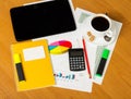 Calculator, notepad, business card, markers and cup coffee on worktable.