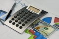 Calculator, one hundred dollars and a pen lying on the diagrams. Royalty Free Stock Photo