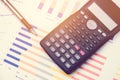 Calculator and pen for data analysis from charts and graph on desk office. business concept