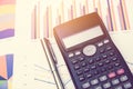 Calculator and pen for data analysis from charts and graph on desk office. business concept