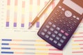 Calculator and pen for data analysis from charts and graph on desk office.