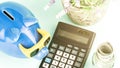 Calculator among piggy bank bottle with dollars and flowers Royalty Free Stock Photo