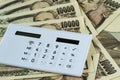 Calculator on pile of japanese yen banknotes as financial safe h
