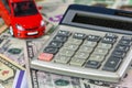 Calculator and red toy car on a variety of national currency banknotes background.  Concept of the cost of purchasing, renting and Royalty Free Stock Photo