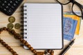 Calculator, rosary, coins, banknotes, book, spectacle and pen on wooden background Royalty Free Stock Photo