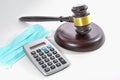 Calculator shows zero, corona face mask and a judge gavel, companies become insolvent during the corona crisis, light gray