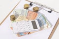 A calculator,stacks of coins and a euro banknotes on a white background