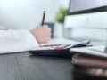 Calculator on table with blurred businesswoman writing for accounting or financial concept