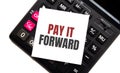 Calculator with text PAY IT FORWARD with white paper Royalty Free Stock Photo