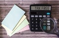 Calculator with the text Tax Free on display, next to stickers and a magnifying glass Royalty Free Stock Photo