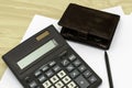 The calculator wallet and fountain pen are on the table on sheets of white paper