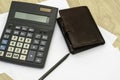 The calculator wallet and fountain pen are on the table on sheets of white paper