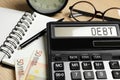 Calculator with word Debt and money on wooden table, closeup Royalty Free Stock Photo