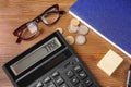 Calculator with word Tax, glasses, coins and notebook