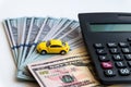 Calculator and yellow toy car on a one hundred dollar bills banknotes background. Concept of the cost of purchasing, renting and