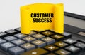 On the calculator is a yellow, twisted paper plate with the inscription - Customer Success