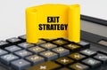 On the calculator is a yellow, twisted paper plate with the inscription - Exit Strategy