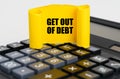 On the calculator is a yellow, twisted paper plate with the inscription - Get Out Of Debt Royalty Free Stock Photo