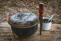 A caldron, a knife and a mug on a wooden stand in outdoor. Hiking set