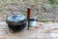 A caldron, a knife and a mug on a wooden stand in outdoor. Tourist.