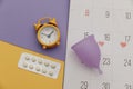 Calendar, alarm clock and menstrual cup with pain relief pills. Woman critical days concept