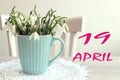 Calendar for April 19: the name of the month April in English, the numbers 19, a bouquet of snowdrops on the background of a